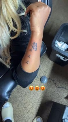 a woman sitting on top of a chair with tattoos on her arm and two small butterflies