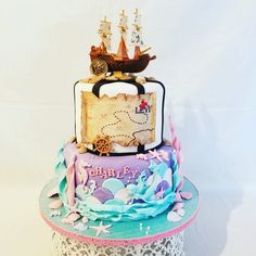 a three tiered cake decorated with an image of a pirate ship and other items