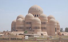 the large building has many domes on it's sides and is beige in color