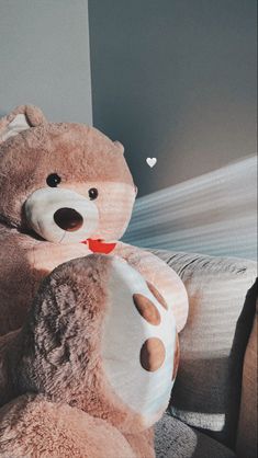 a large teddy bear sitting on top of a bed