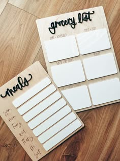 two sticky notes sitting on top of a wooden table next to each other with writing on them