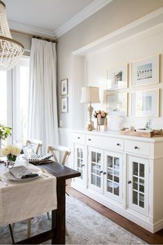 a dining room with white furniture and pictures on the wall