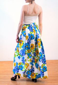 "This is a beautiful and bright 1970s vintage \"Leslie Fay\" maxi skirt with a Hawaiian floral print and a matelassé weave! It's a wrap skirt with two buttons at the waist and an attached long fabric sash. It has interesting box pleats in the back that give it added volume. The weave is textured with white on white jacquard flowers and a bright blue, blue-purple, chartreuse green and sunny gold tropical design. Perfect for summer pool parties, or wear as a beach cover-up over your swimsuit! The Retro Long Blue Skirt, Retro Blue Party Skirt, Vintage Blue Flared Skirt, Spring Maxi Skirt For Garden Party, Spring Floor-length Pleated Skirt, Spring Floor-length Lined Skirt, Retro Blue Floral Print Skirt, Blue Retro Skirt With Floral Print, Retro Blue Spring Maxi Dress