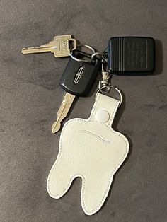 a keychain with a tooth shaped leather case and keys attached to it, sitting on a table