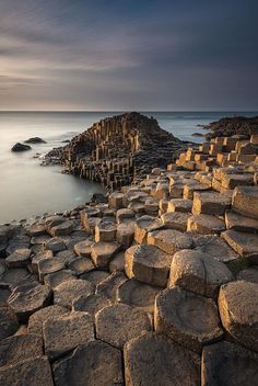 the giant stones are in the water by the rocks and they look like they have been built into the ground