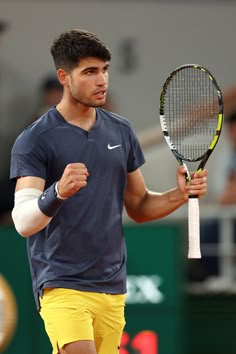 a man holding a tennis racquet on top of a tennis court with people in the background