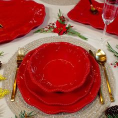 a table set for christmas with red plates and silverware