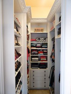 an open closet filled with lots of clothes and shoes on top of white shelving