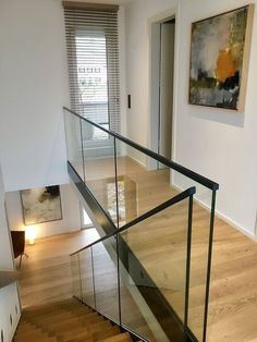 a staircase with glass railing and wood flooring