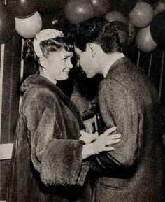 an old black and white photo of two people standing together in front of some balloons