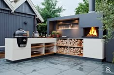 an outdoor bbq grill with firewood stacked on the counter and storage area in front