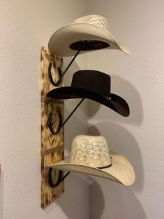 three hats are hanging on the wall next to a hat rack with two hats in it