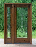 an open wooden door with decorative glass on the front and side doors, in front of some trees