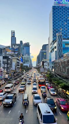 a busy city street filled with lots of traffic and tall buildings in the back ground