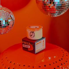 a box of cream sitting on top of an orange stool in front of disco balls