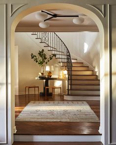 an archway leading to a living room and dining area with stairs in the center, along with two tables on either side