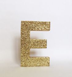 the letter e is made out of gold glitters and sits on a white surface