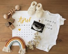 a baby's first birthday outfit and other items laid out on a wooden floor