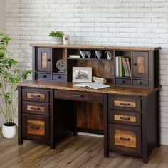 a wooden desk with two drawers and a book shelf on top of it in front of a brick wall