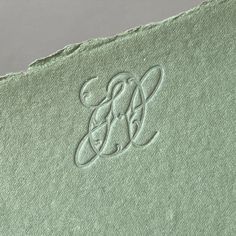 the monogrammed logo is on an old green piece of paper