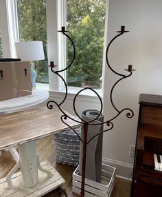 a tall metal candle holder sitting on top of a wooden table next to a window