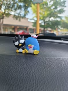 two small figurines sitting on the dashboard of a car