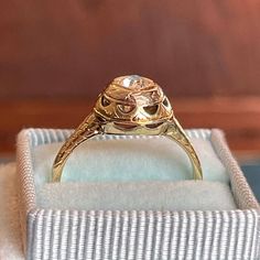 a gold ring sitting on top of a white box with a diamond in the middle