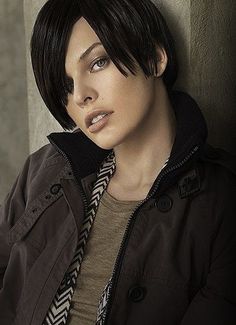 a woman leaning against a wall wearing a jacket