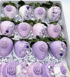 a box filled with lots of purple heart shaped cake covered in frosting and flowers