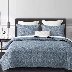 a bed with blue and white comforters in a bedroom next to a night stand