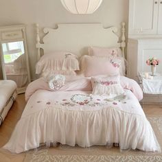 a white bed with pink comforter and pillows