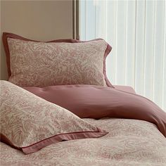 a bed with pink sheets and pillows on top of it