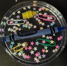 a plastic container filled with different colored paper clips and scissors on top of a black surface