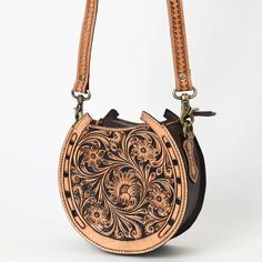 Introducing the Saddle & Stitch Handbag, a beautifully crafted accessory that embodies the spirit of the west. Made from high-quality tooled leather, this horseshoe-shaped canteen handbag showcases exquisite detailing that adds a touch of rustic elegance to any outfit. Designed for both style and functionality, the Saddle & Stitch Handbag features a spacious interior, perfect for keeping your essentials organized while on the go. The adjustable strap allows for versatile carrying options, whethe Canteen Purse, Round Purse, Saddle Stitch, Tooled Leather Purse, Saddle Pad, Unique Purses, Dog Products, Pets For Sale, Tooled Leather