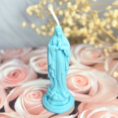 a blue candle sitting on top of pink roses