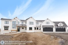 a large white house sitting on top of a dirt field under a blue sky with clouds