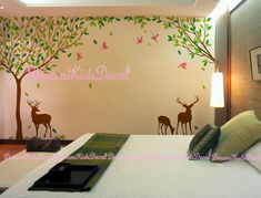 a bed room with a neatly made bed and wall decals on the walls behind it