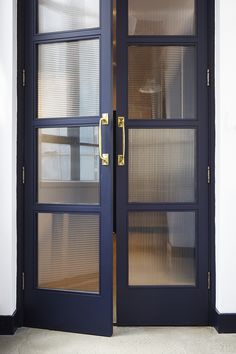 an open door with glass panels and gold handles