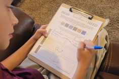 a young boy is writing on a clipboard with marker and paper attached to it