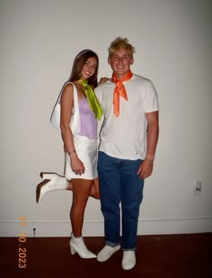 a man standing next to a woman in a white shirt and orange neck tie on