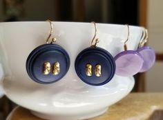 three pairs of earrings are sitting on a white bowl