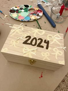 a wooden box sitting on top of a table covered in crafting supplies and paint