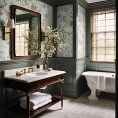 a bathroom with green walls and floral wallpaper on the walls, along with a claw foot tub