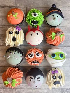 cupcakes decorated with halloween themed icing are arranged in a circle on a wooden surface