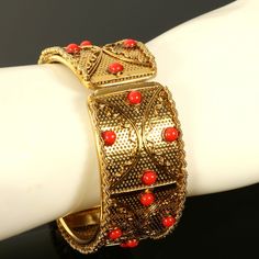 Vintage Metal Mesh Hinged Bangle Wide Bracelet Red Cabochon Gold Tone  Here's a wide metal mesh hinged bangle bracelet in gold tone.  Textured with metal bars and plastic round cabochon mountings. No maker hallmarks found. Condition: Previously owned, good original condition. One of the cabochon mountings is off center as seen in photos - as this bracelet was handmade constructed.  The hinge is in perfect working order. Measures Approximately: Interior Circumference 7-3/8 in. Bracelet Width is 1 in. Thank you for visiting Clara's Chic Boutique! More vintage jewelry: https://www.etsy.com/shop/ClarasChicBoutique?ref=seller-platform-mcna0v§ion_id=13953588 Vintage Jewelry, 1980s Jewelry, Vintage Bracelet, Bangle Bracelet, Hinged Bangle, Mesh Bangle, Wide Bracelet, Red Cabochon, Textured Bangle 1980s Jewelry, Wide Bracelet, Vintage Bracelet, Metal Bar, Metal Mesh, Bracelet Bangle, Hinged Bangle, Vintage Bracelets, Jewelry Vintage