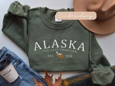 Embrace the spirit of the Last Frontier with our meticulously embroidered Alaska sweatshirt, a cozy tribute to the wild and beautiful North. Stay warm and show your love for Alaska in style with this must-have addition to your wardrobe. ✨DESCRIPTION✨  🌟GILDAN 18000 Unisex Sweatshirt - Embroidered design *100% cotton (Sport Grey is 90% cotton, 10% polyester; Ash Grey is 99% cotton, 1% polyester, heather colors are 50% cotton, 50% polyester. *Sweatshirts are in UNISEX sizing. Select your usual size for a more fitted look, or size up for a more relaxed fit. *Please note that the embroidery design has a backing on the inside of the sweatshirt to support the fabric and stitches. *Fabric Weight 5.0-5.3 oz/yd² (170-180 g/m²) *pre-shrunk jersey knit, air jet spun yarn for a soft feel & reduced pi Alaska Sweatshirt, Alaskan Vacation, Alaska Moose, Elizabeth Bennet, Family Cruise, Alaska Cruise, Womens Sweater, Sweater Gift, Family Trip