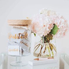 a vase filled with pink flowers sitting on top of a white table next to a book