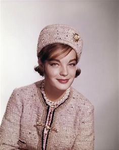 a woman wearing a knitted hat and jacket with pearls on the front, smiling