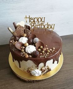 a birthday cake with chocolate icing and nuts on top, sitting on a table