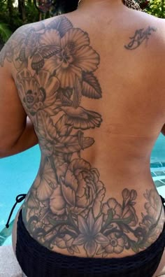 the back of a woman's body with flowers and birds tattooed on her back